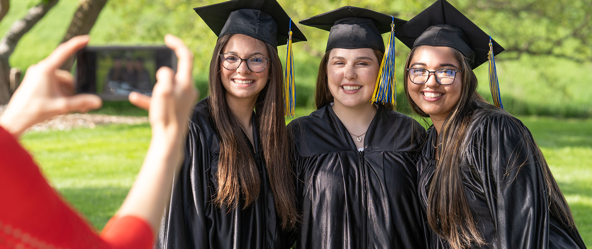 Students dressed in a cap and gown posing for a picture