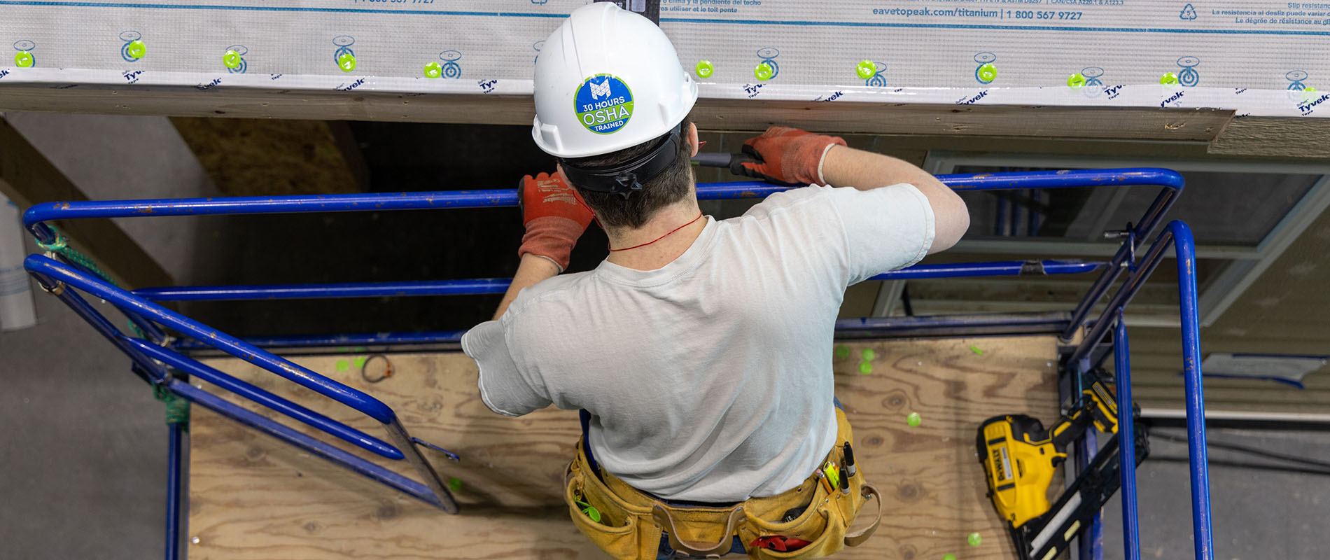 Student with hard hat working a house
