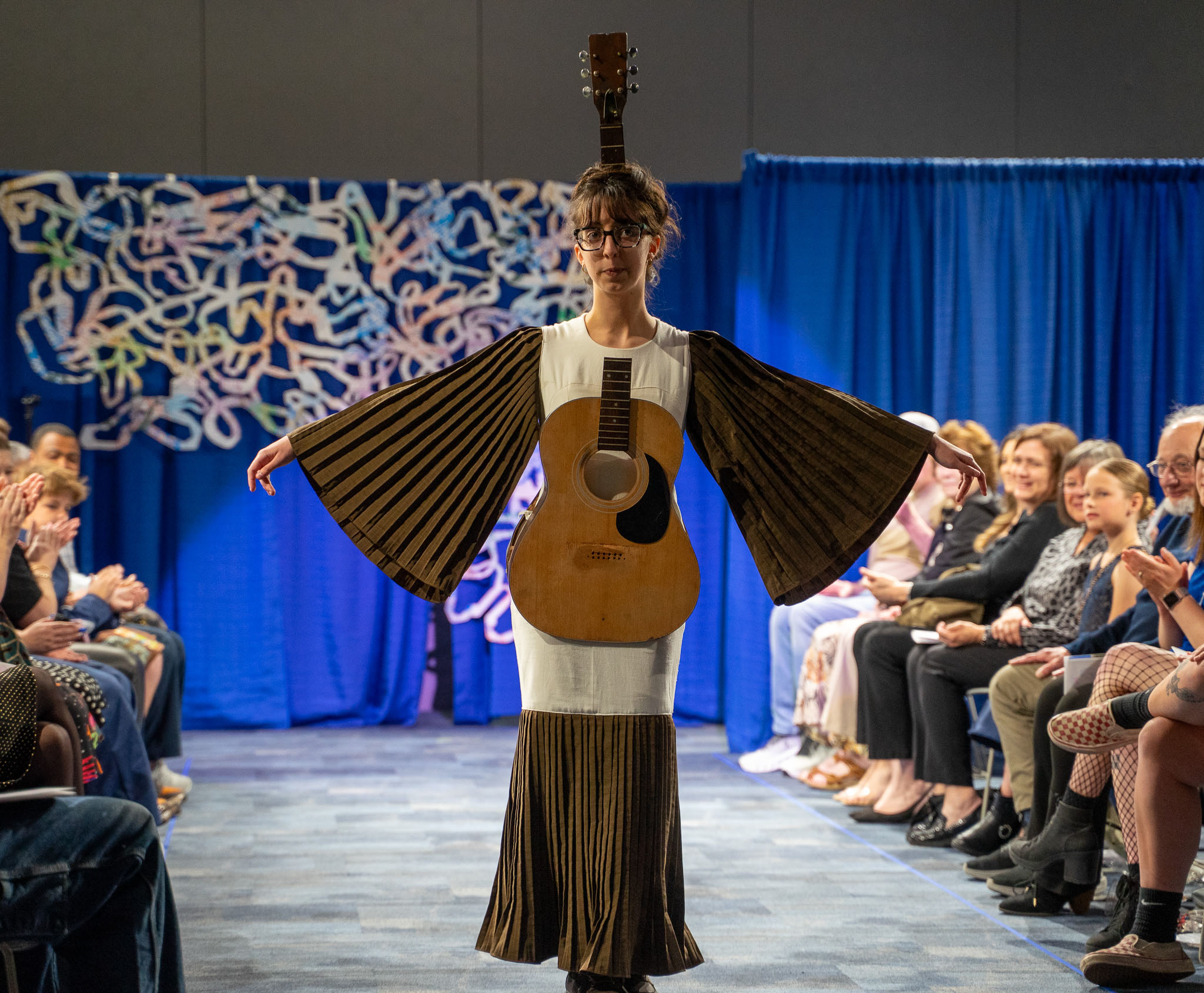 Student model in guitar based dress posing on runway