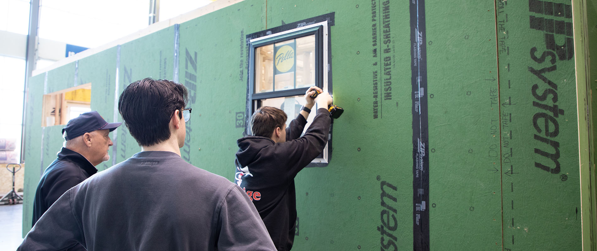 Group of students working on installing windows to a house being constructed