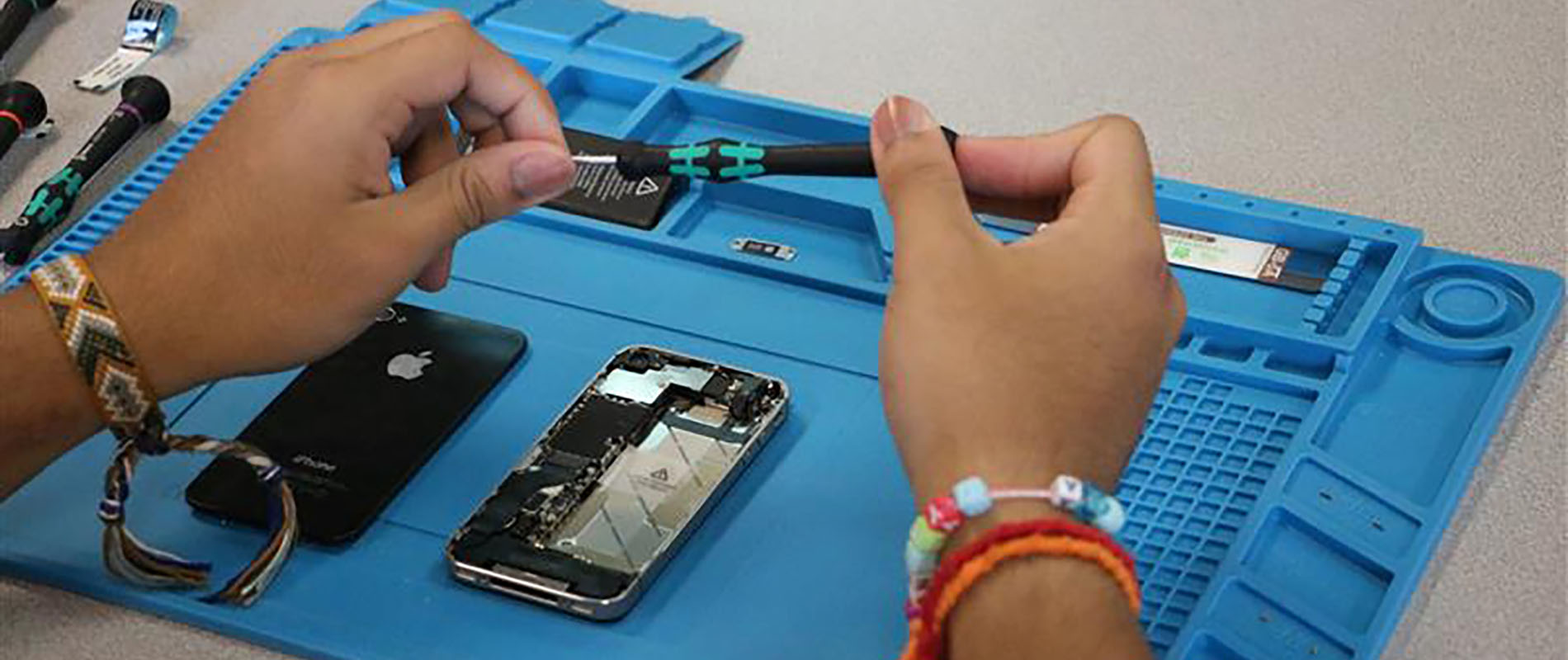 Close up photo of a student repairing a smart phone