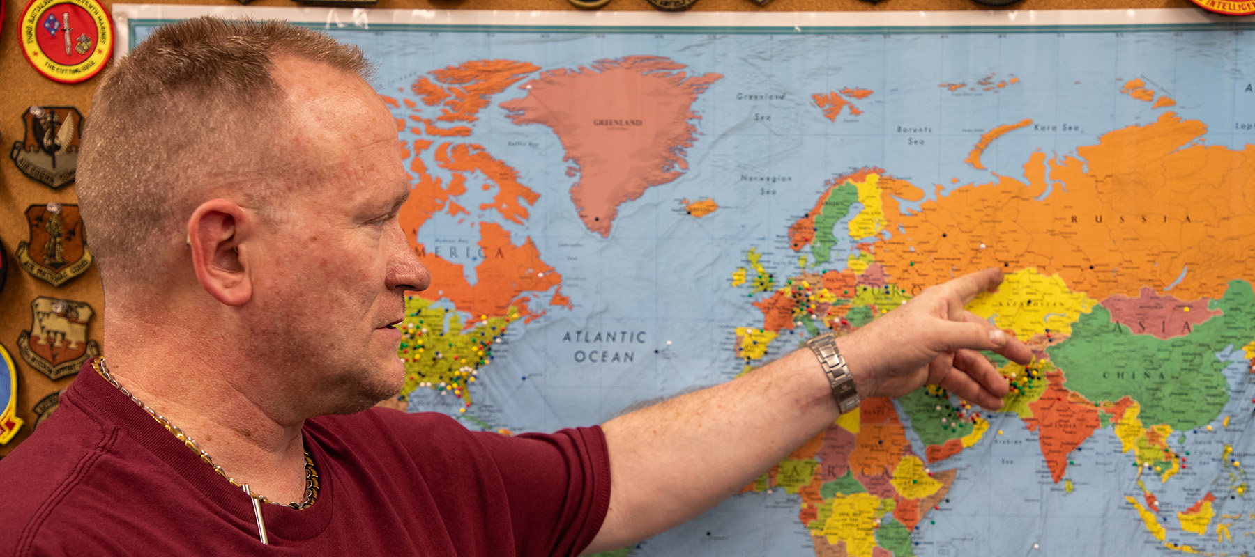 Talkington standing in front of a world map at the Veterans and Military Resource Center on the South Omaha Campus, pointing to the Baltic region, where he spend significant time during his military service