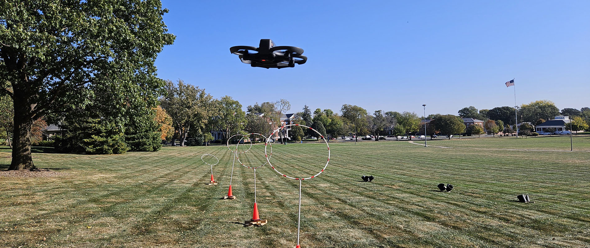 A drone flies over an obstacle course on the Fort Omaha Campus Parade Grounds