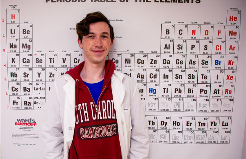 Student standing in front on the periodic table