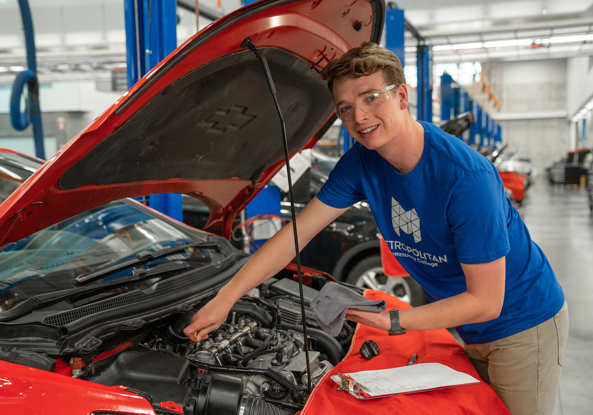 Happy Male Student Working on Red Car