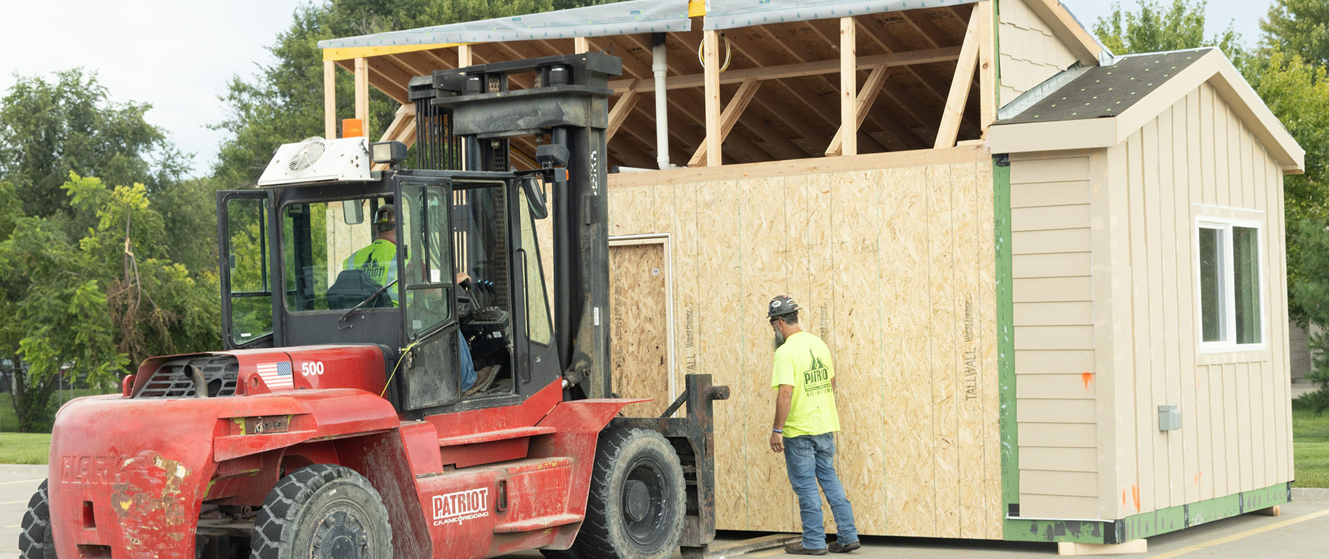 Student on a forklift lifting up a house under construction